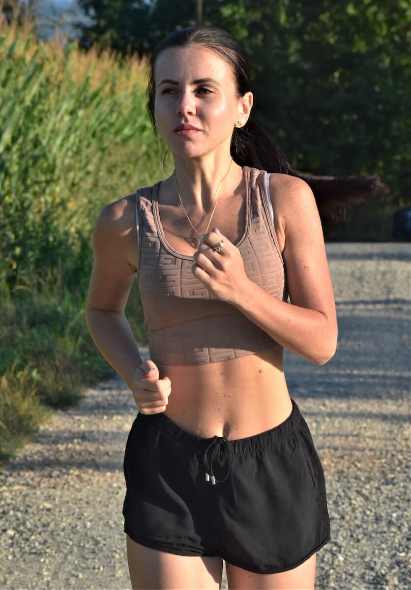 a woman running down a road in a bra top